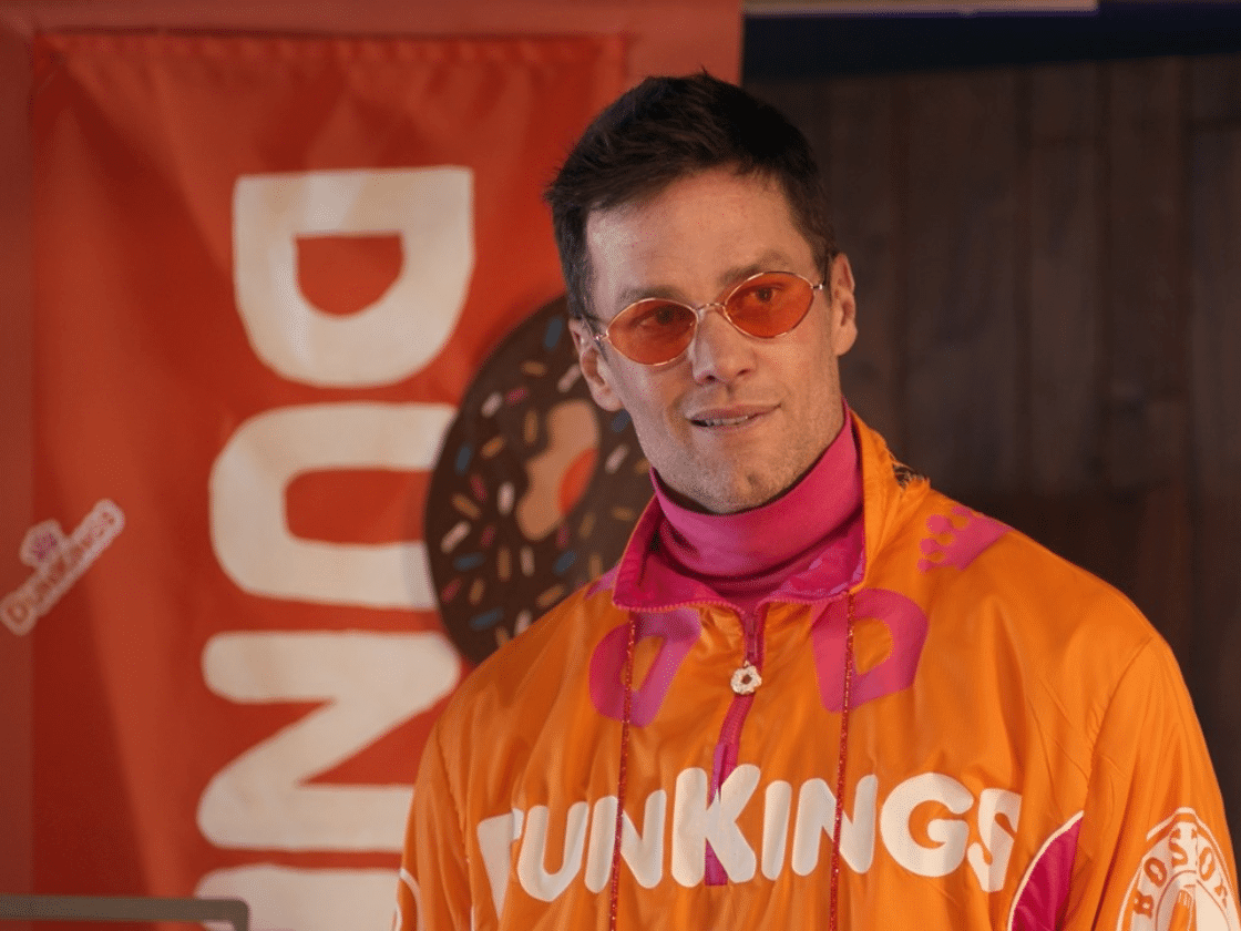 Super Bowl champion quarterback Tom Brady wearing orange Dunkin’ campaign apparel at a Super Bowl-themed brand event.